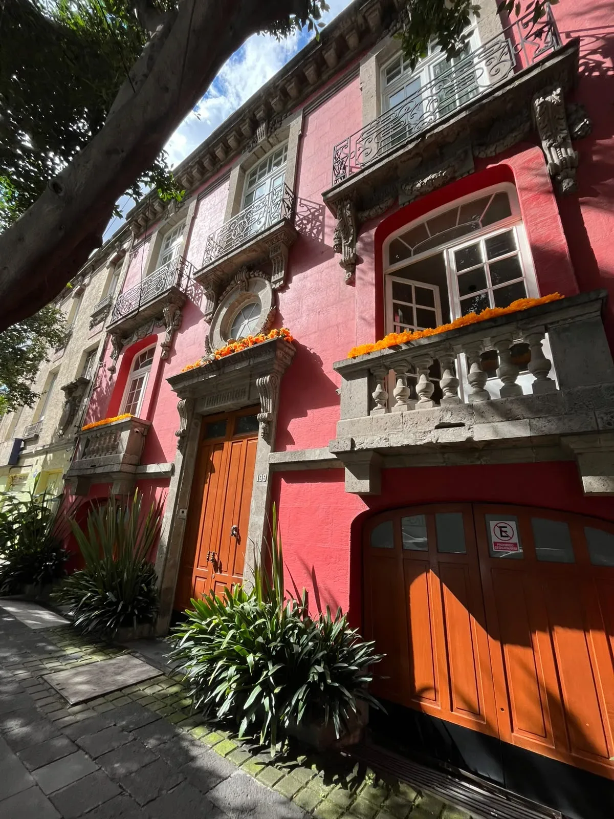Fachada de Casa Goliana, casona de principios del siglo XX con muros rojos y puertas de madera en Roma Norte