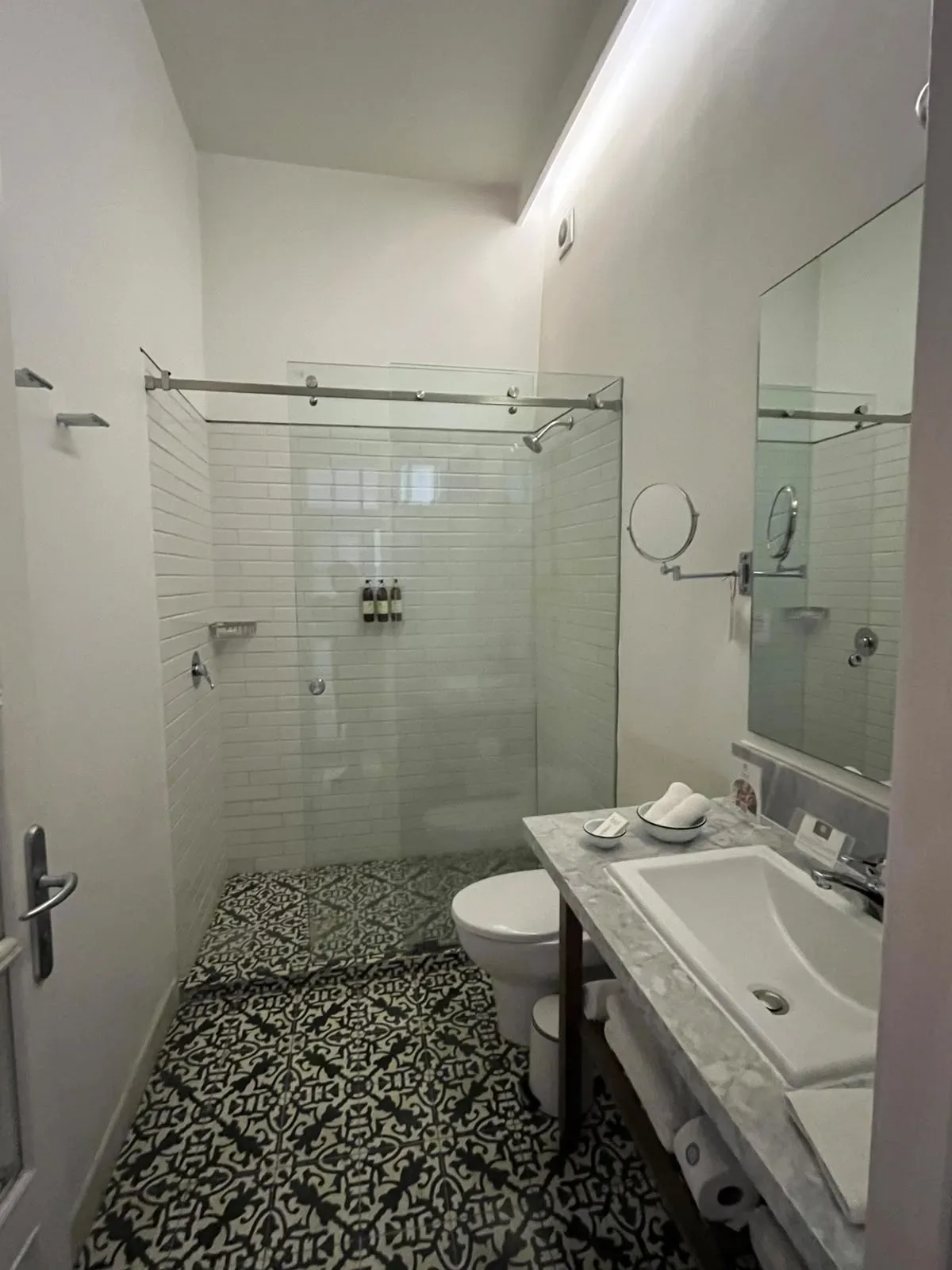 Baño de Casa Goliana con regadera de cristal, azulejo blanco y piso de mosaico de pasta