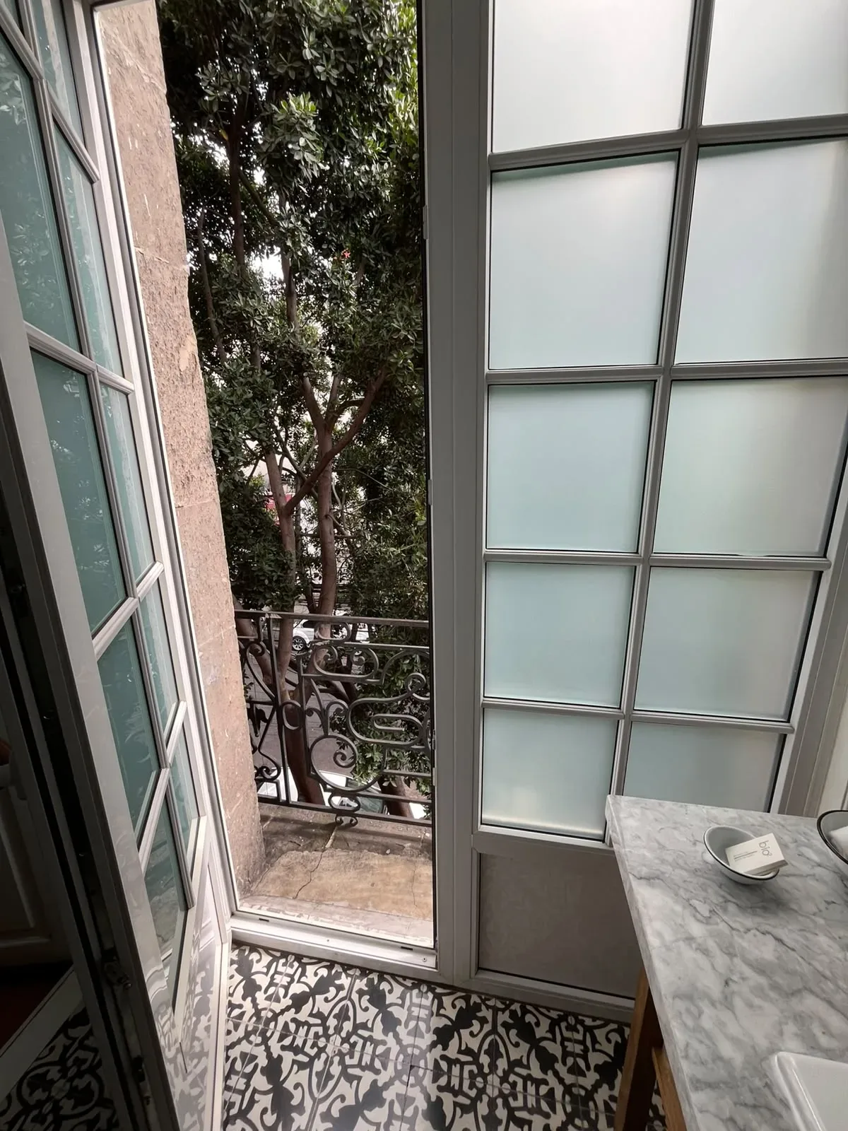 Ventanal abierto de una habitación de Casa Goliana hacia los árboles de la calle