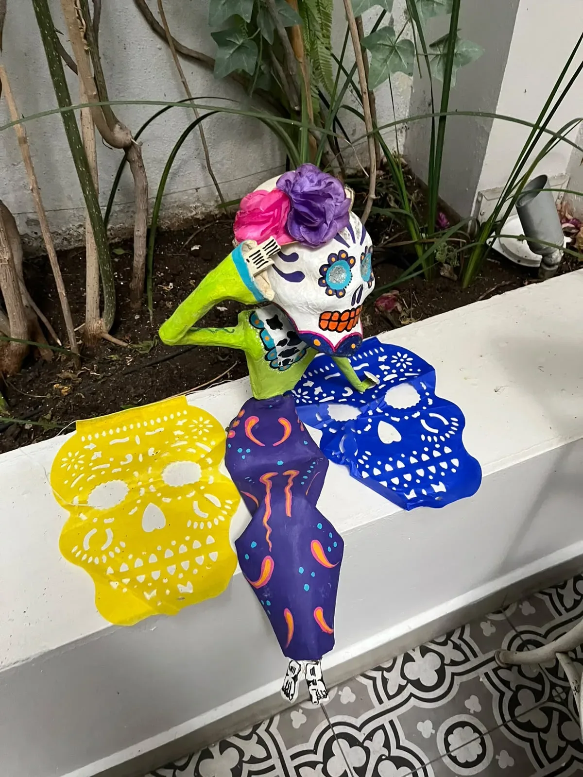 Calaveras de papel con flores y papel picado decorando una jardinera de Casa Goliana